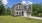 a grey home with a driveway grass and trees