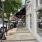 a sidewalk next to a row of shops and an American flag