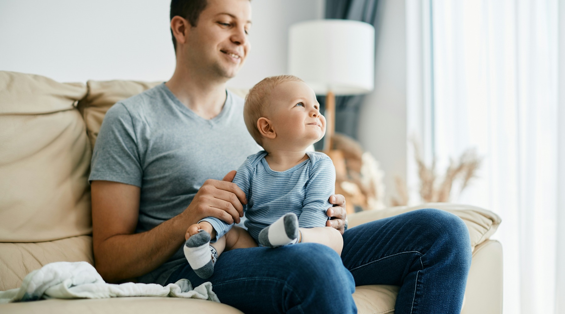 Father playing with baby on a sofa in a home for rent Father playing with baby on a sofa in a home for rent