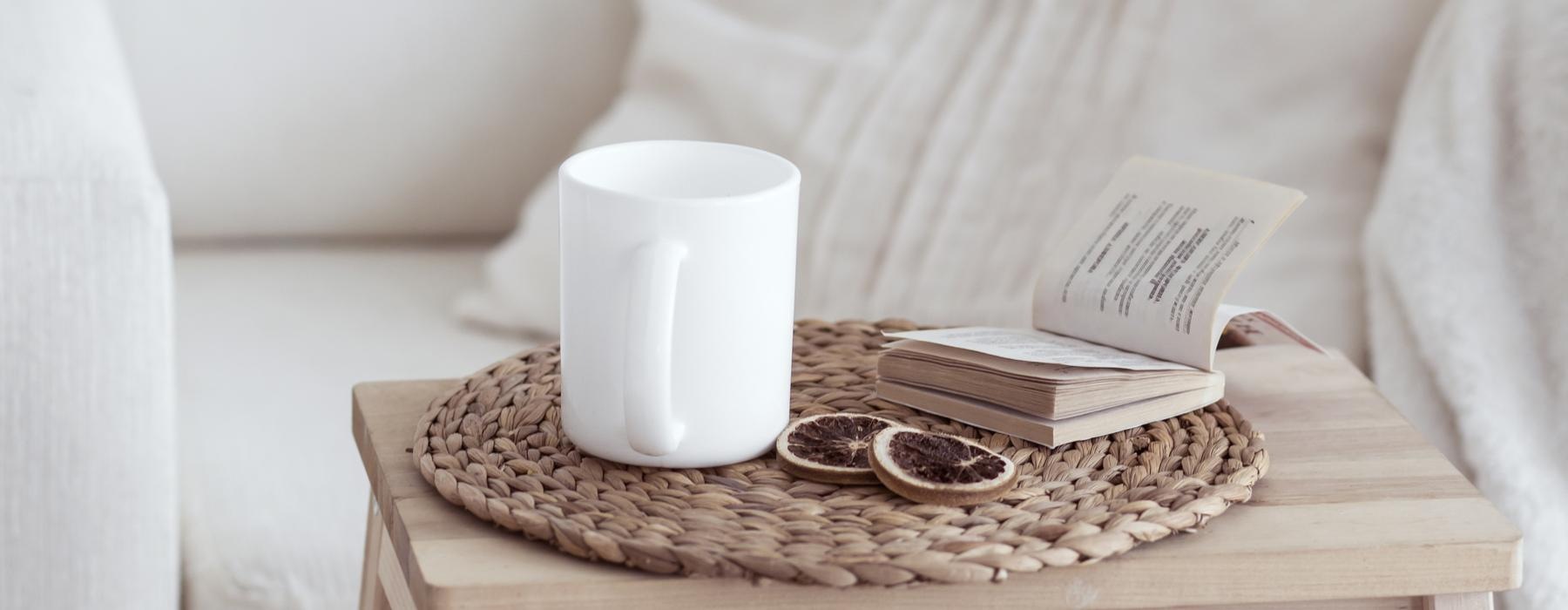 a white couch with a white pillow and a white coffee cup on it